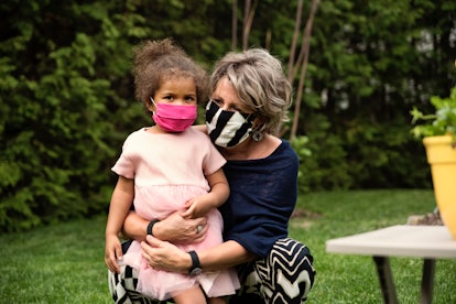 A grandmother holding her granddaughter while they are wearing masks during the Covid-19 pandemic