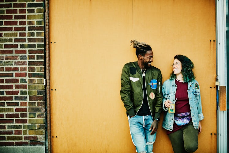 Young woman smiling at the Aquarius man she's dating against a wall.