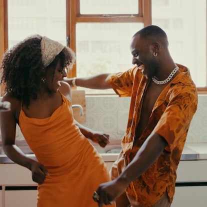 Young woman and Virgo man in love, dancing in their kitchen.