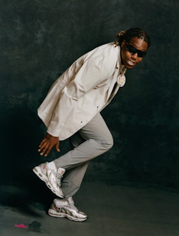 Don Toliver wearing sunglasses, a large white shirt, gray pants and gray reflective Nikes