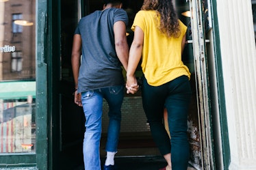Young woman holding hands with the Aquarius man she's dating as they enter a restaurant.
