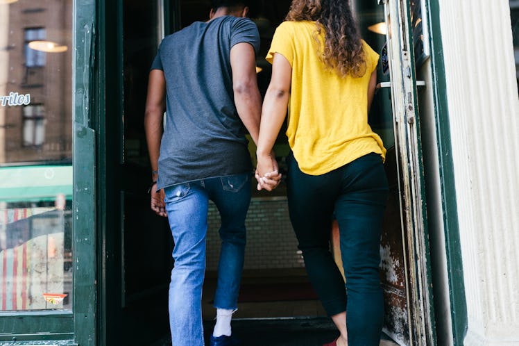 Young woman holding hands with the Aquarius man she's dating as they enter a restaurant.