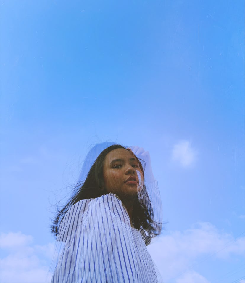 Young misunderstood Aquarius woman against a blue sky.