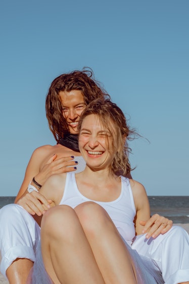 2 sisters smiling and hugging at the beach before posting on Instagram with a comment on sister pic.