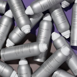 Living Proof Advanced Clean Dry Shampoo cans piled up against purple background