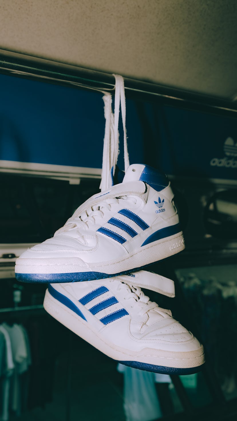 A pair of the Adidas Forum low sneakers tied on the arm rail of a bus