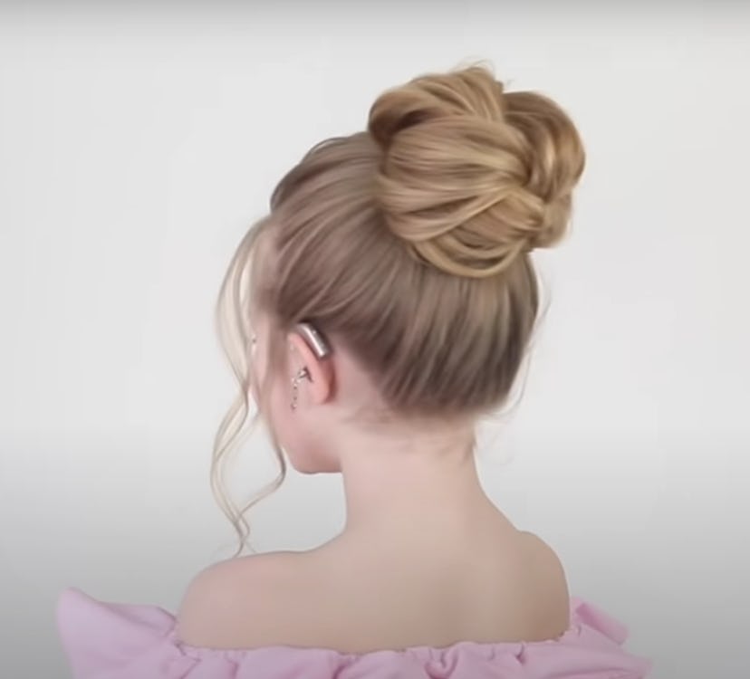 Back-side view of little girl with messy bun high on her head