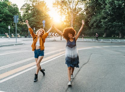 2 friends walking together holding hands in the city at sunset before posting funny birthday caption...