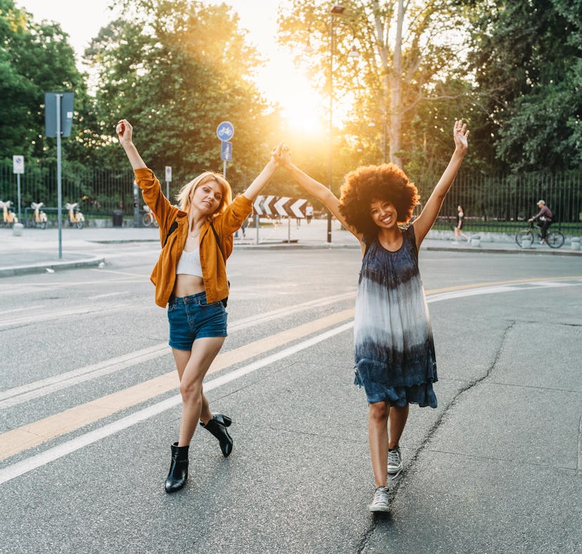 2 friends walking together holding hands in the city at sunset before posting funny birthday caption...
