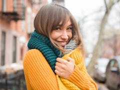 Flirty young woman wearing a sweater and a scarf before posting a pic on Instagram with a flirty cap...