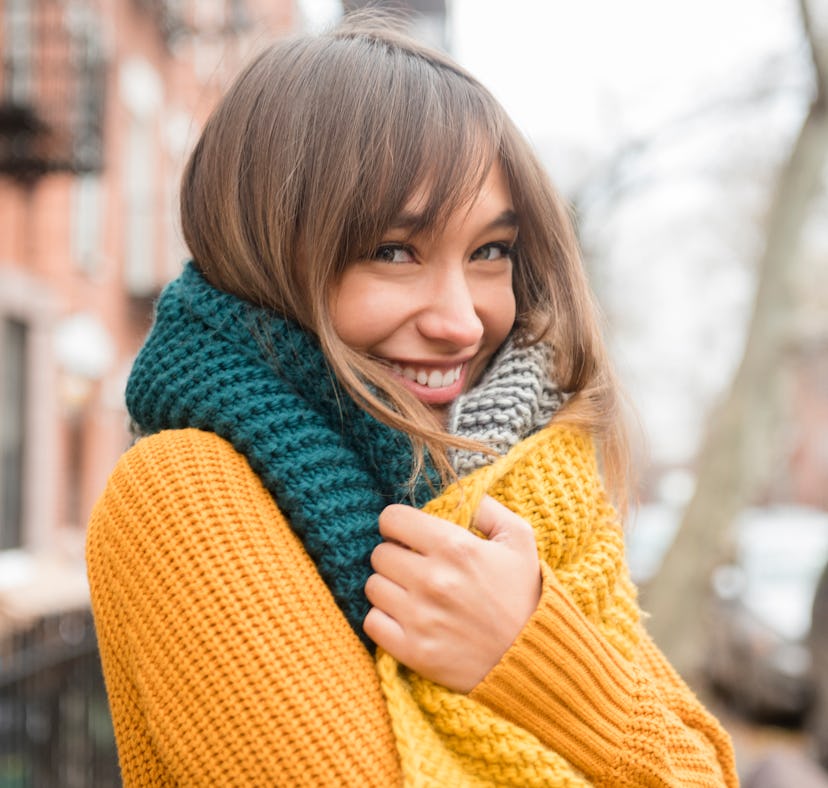 Flirty young woman wearing a sweater and a scarf before posting a pic on Instagram with a flirty cap...