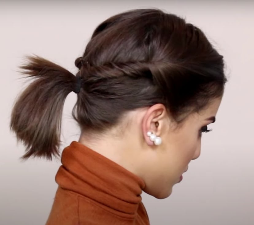 Side view of a woman with short hair pulled back in a ponytail with twists 