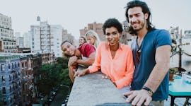 A group of friends smiling for the camera on the roof of someone's apartment, in need of rooftop Ins...