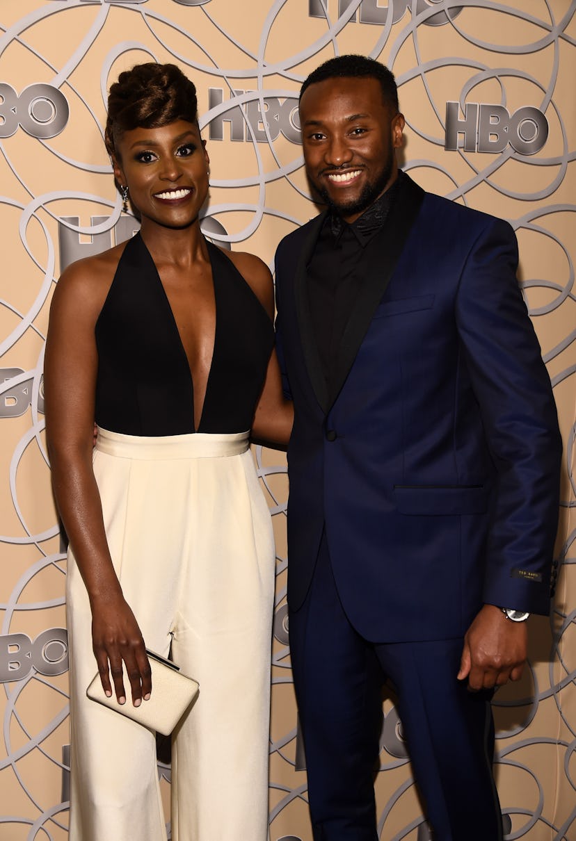 Issa Rae in a black top and white trousers and Louis Diame in a navy suit and black shirt