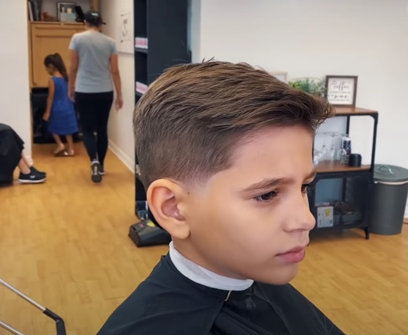Little boy in barber chair with freshly cut hair swooped to the side