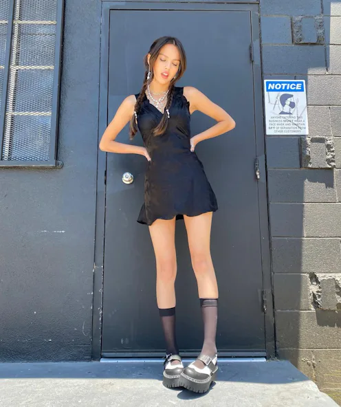 Olivia Rodrigo wearing a black slip dress, opaque socks, and platform Mary Jane shoes.