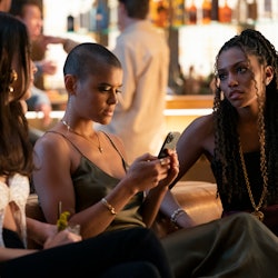 Characters from the Gossip Girl reboot sit on a couch at a club. Of the three girls, Julien, a Black...