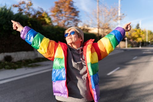 Woman in rainbow coat posing in the middle of the street.