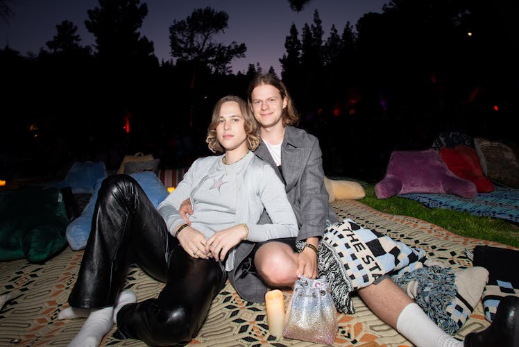 Tommy leaning on Lucas on a blanket outside