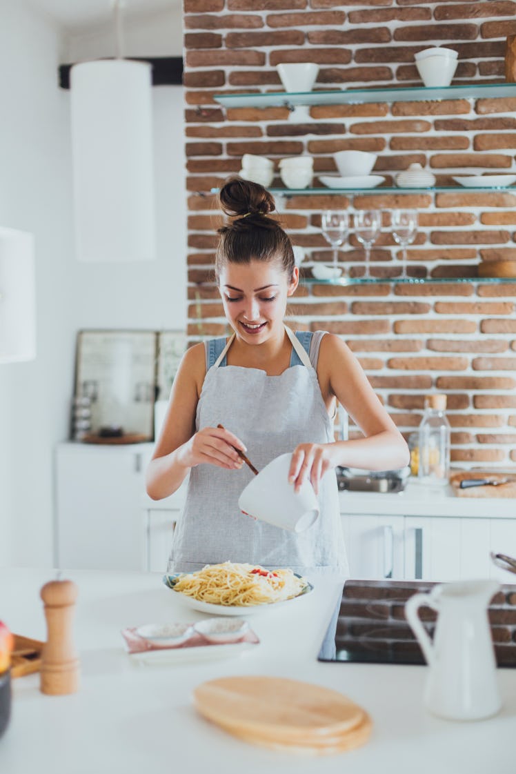 Young woman making TikTok's oven baked pasta recipes in her kitchen.