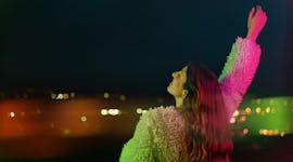 Young woman looking out over the city on her 29th birthday before posting on Instagram with a 29th b...