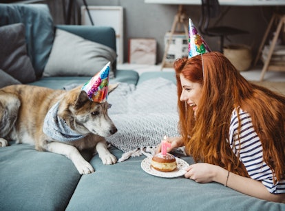 Young woman celebrating her puppy's birthday with a cake and dog birthday Instagram captions.