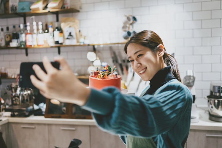 Young woman taking a selfie with her cake before posting on Instagram with birthday cake quotes, cap...