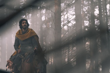 Dev Patel riding a horse through the woods in The Green Knight
