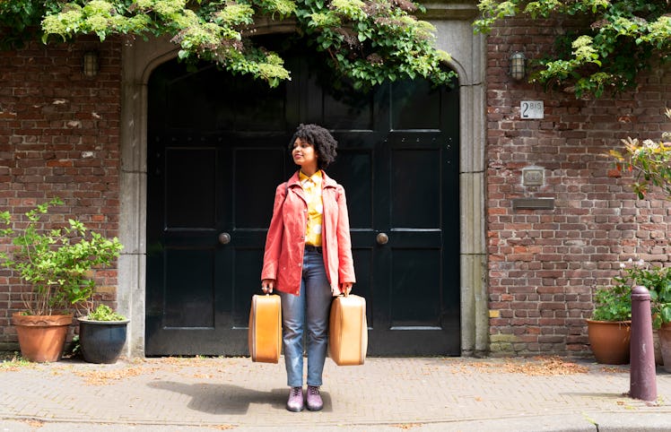 Young woman holding two suitcases, ready to post a pic with travel captions for Instagram.