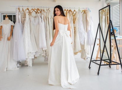 Young woman saying yes to the dress, trying on a gown before posting a picture on Instagram with a w...