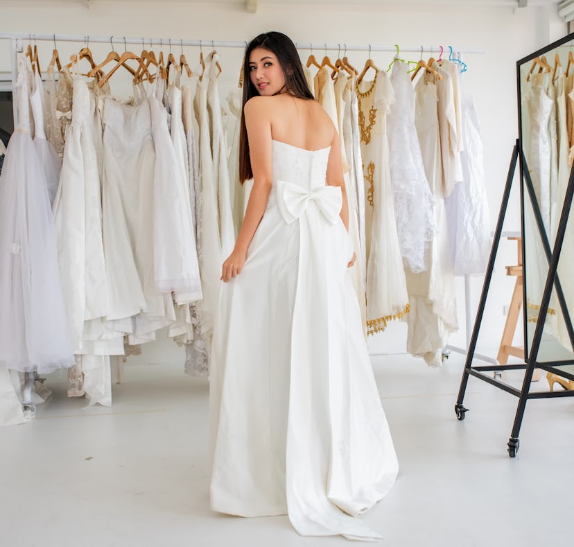 Young woman saying yes to the dress, trying on a gown before posting a picture on Instagram with a w...
