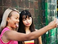 2 young women taking a fun selfie before posting on Instagram with birthday captions for best friend...