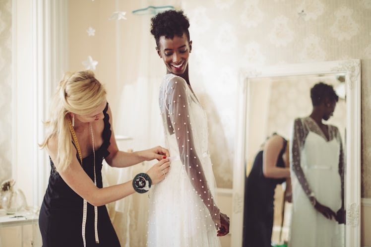 Young woman trying on her wedding dress before posting a pic on Instagram with a say yes to the dres...