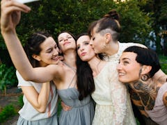 Bridesmaids taking a selfie with the brides before posting a pic on Instagram with wedding captions.