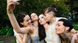 Bridesmaids taking a selfie with the brides before posting a pic on Instagram with wedding captions.