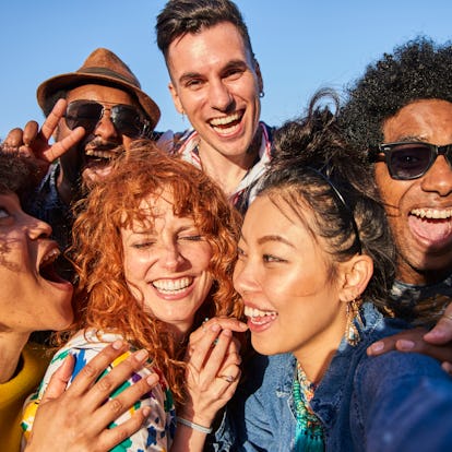 A group of friends laughing and taking a selfie at their high school reunion before posting on Insta...