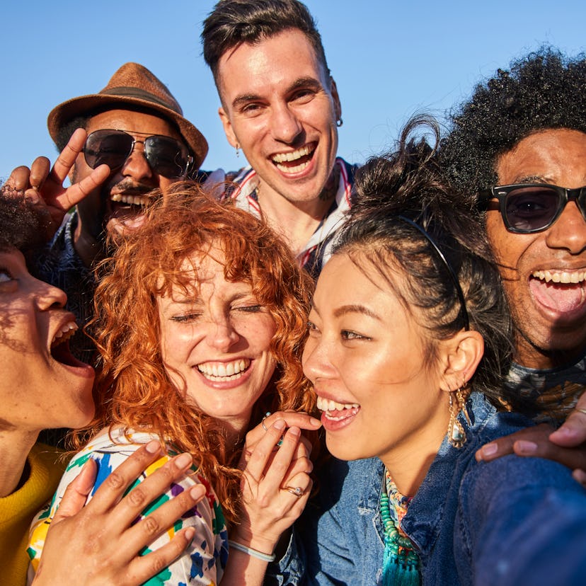 A group of friends laughing and taking a selfie at their high school reunion before posting on Insta...