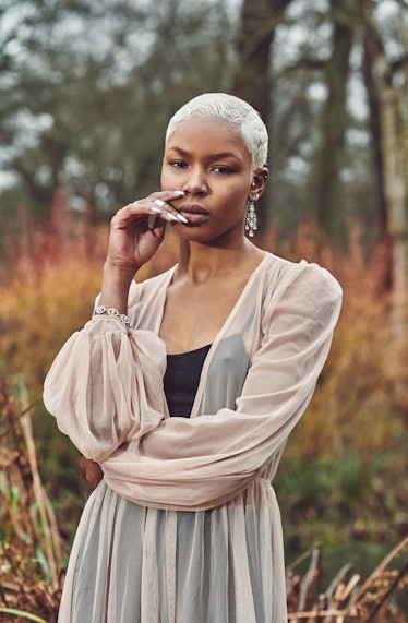 Young woman with platinum blonde hair, posing in a field before posting an Instagram with with a blo...
