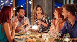 A group of friends posing around a birthday cake before posting on Instagram with a birthday cake qu...