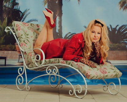 Jennifer Coolidge lying on a floral sunbed in a red Vex coat, leopard Miscreants gloves and red Casa...
