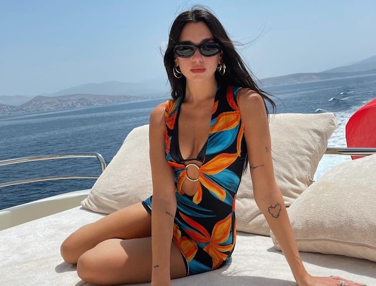 Dua Lipa on a yacht in a floral-patterned mini dress, with a hoop in the middle 