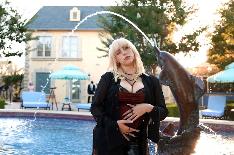 Billie Eilish posing next to a fountain at the celebration for her new album "Happier Than Ever"