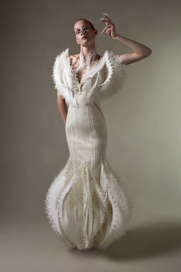 A model in a white Iris Van Herpen gown with no sleeves and the front shaped like wings 