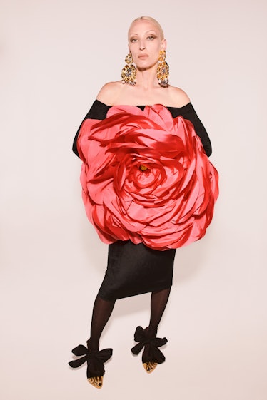 A model in a black Schiaparelli gown with a red rose in the middle 