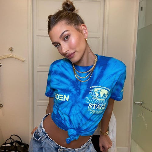 Hailey Baldwin in a blue top and golden necklace, wearing a chic summer updo