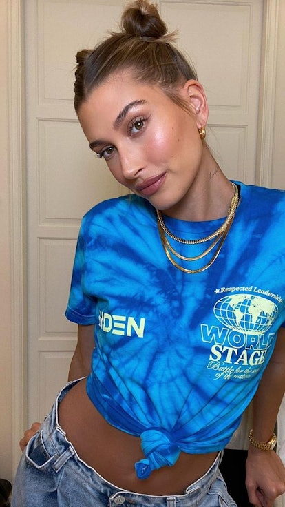 Hailey Baldwin in a blue top and golden necklace, wearing a chic summer updo