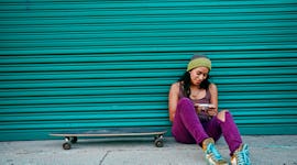 Young woman looking at throwback pictures on her phone, wondering what throwback caption or quote to...