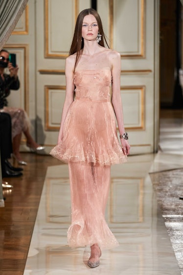 A model walking the runway in a blush pink, semi-sheer Armani Privé gown 