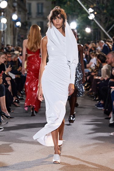 A model walking the runway in a white shimmery Alaïa gown 