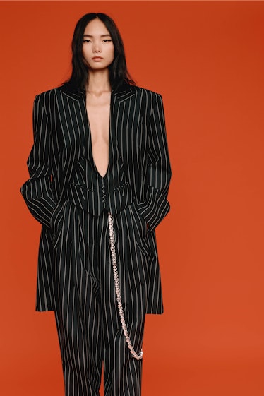A model in an oversized black Alexandre Vauthier three-piece suit with stripes and a chain on one po...